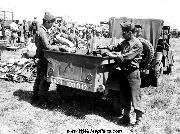 Members of Company C, 100th Infantry Battalion, 442nd Regimental Combat Team and Company D, 100th Infantry Battalion, 442nd Infantry Regiment load confiscated enemy material into a Jeep Trailer which is run down a line of material at the 5th Army concentration area in Brescia Area, Italy on 18 May 1945.